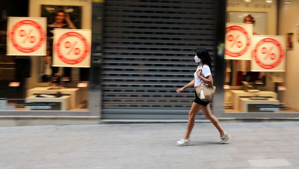 Una mujer con una máscara facial pasa junto a una tienda cerrada en la ciudad de Lleida. 13 de julio de 2020 - Sputnik Mundo