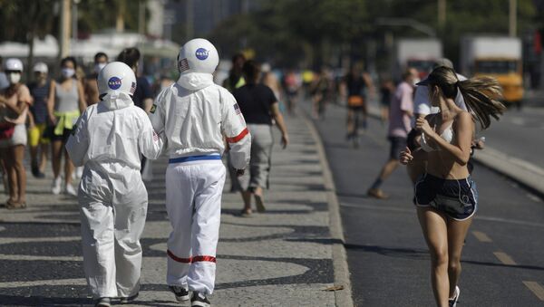 Los brasileños Tércio y Alicéia pasean por una playa en Río de Janeiro con sus trajes de astronauta - Sputnik Mundo
