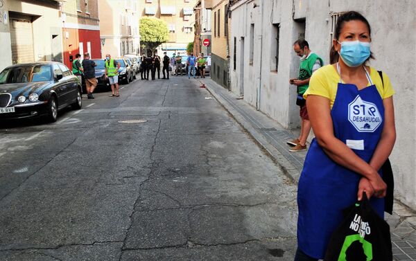 Una asistente al desahucio de Vallecas, en Madrid, esperando con la policía al fondo - Sputnik Mundo