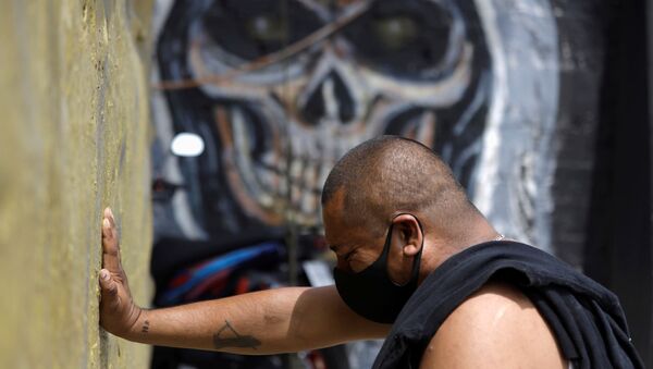 Un hombre con mascarilla rezando a la Santa Muerte en Ciudad de México - Sputnik Mundo