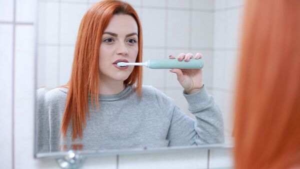 Una chica cepillándose los dientes - Sputnik Mundo