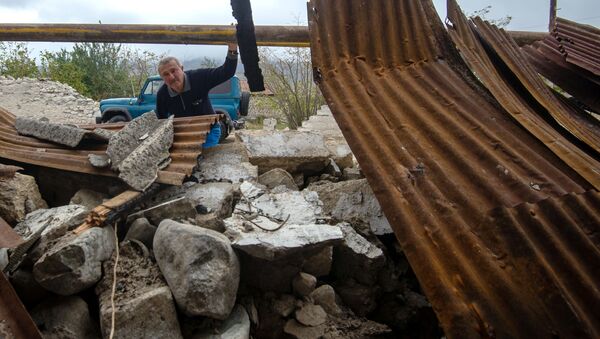 Мужчина у хозяйственной постройки, разрушенной в результате обстрела общины Иванян Нагорного Карабаха - Sputnik Mundo