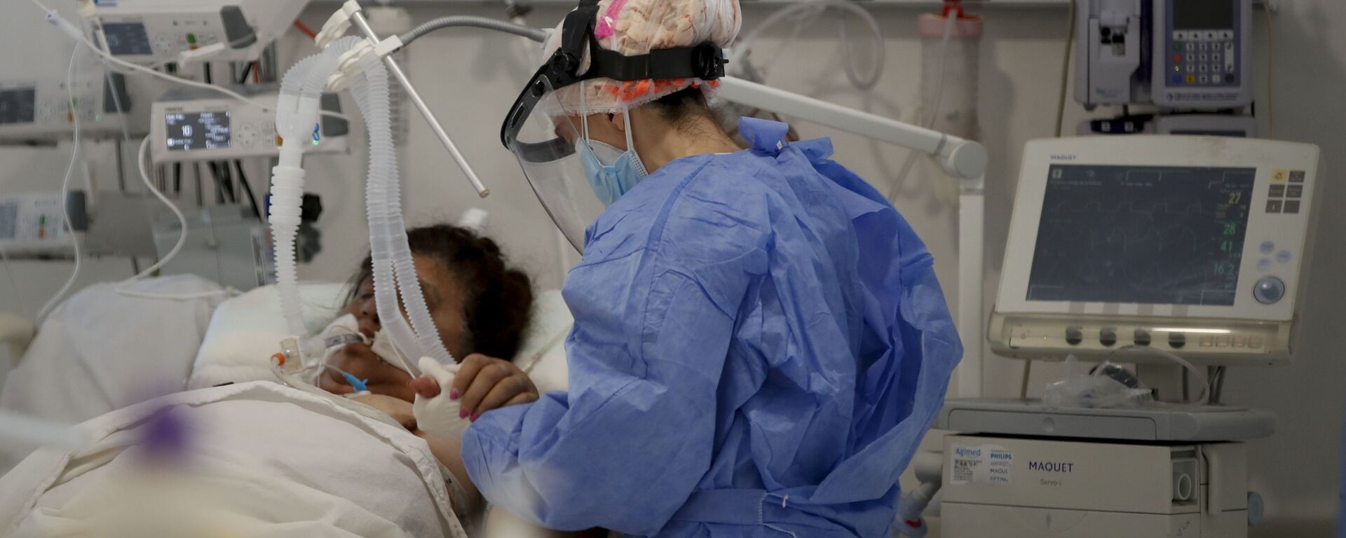 Una trabajadora de la salud atiende a un paciente en una unidad de cuidados intensivos designada para personas infectadas con coronavirus en un hospital en Buenos Aires (Argentina) - Sputnik Mundo, 1920, 15.04.2024