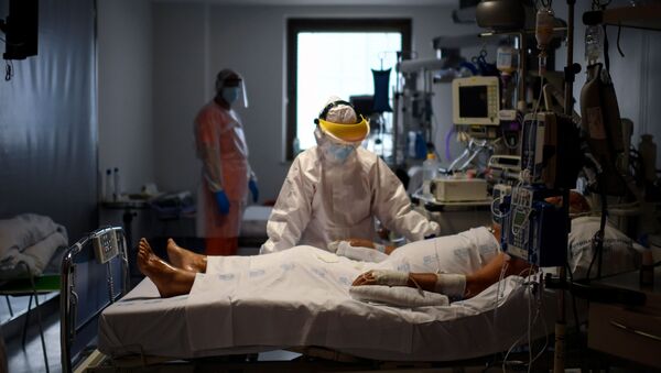Sanitarios atendiendo a un paciente con coronavirus en España - Sputnik Mundo