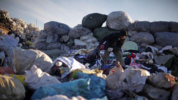 Un hombre chino revisa la ropa desechada en un centro de reciclaje en Pekín, China. - Sputnik Mundo