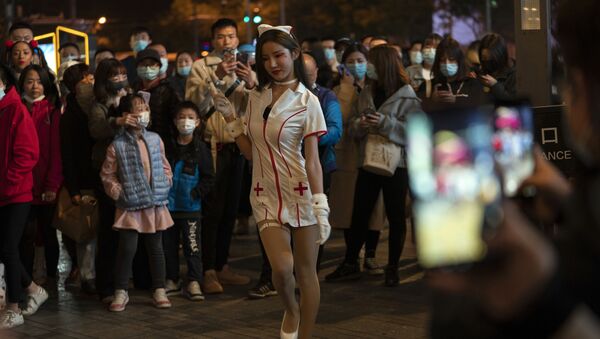 Девушка в костюме медсестры выступает перед толпой в ночь Хэллоуина в торговом районе Пекина - Sputnik Mundo