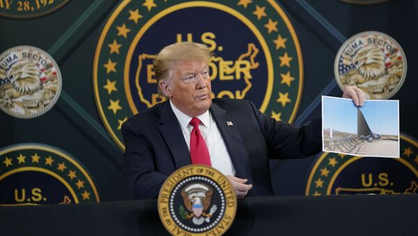 El presidente de EEUU, Donald Trump, sostiene la foto de la construcción del muro fronterizo con México - Sputnik Mundo