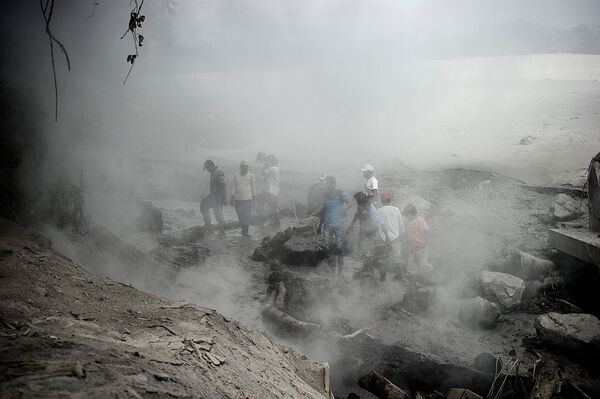 Unos hombres tratan de averiguar los daños causados por la erupción del volcán Semeru. - Sputnik Mundo