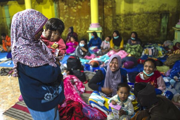 Unas personas, en su mayoría mujeres y niños, se refugian en un salón comunitario después de ser evacuados de sus casas debido a la erupción del volcán Semeru. - Sputnik Mundo