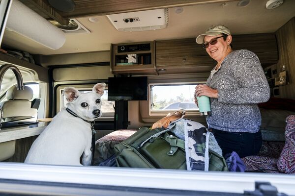 Una mujer con un perro en su autocaravana en un punto de evacuación temporal de la Cruz Roja en el condado de Orange, estado de California. - Sputnik Mundo