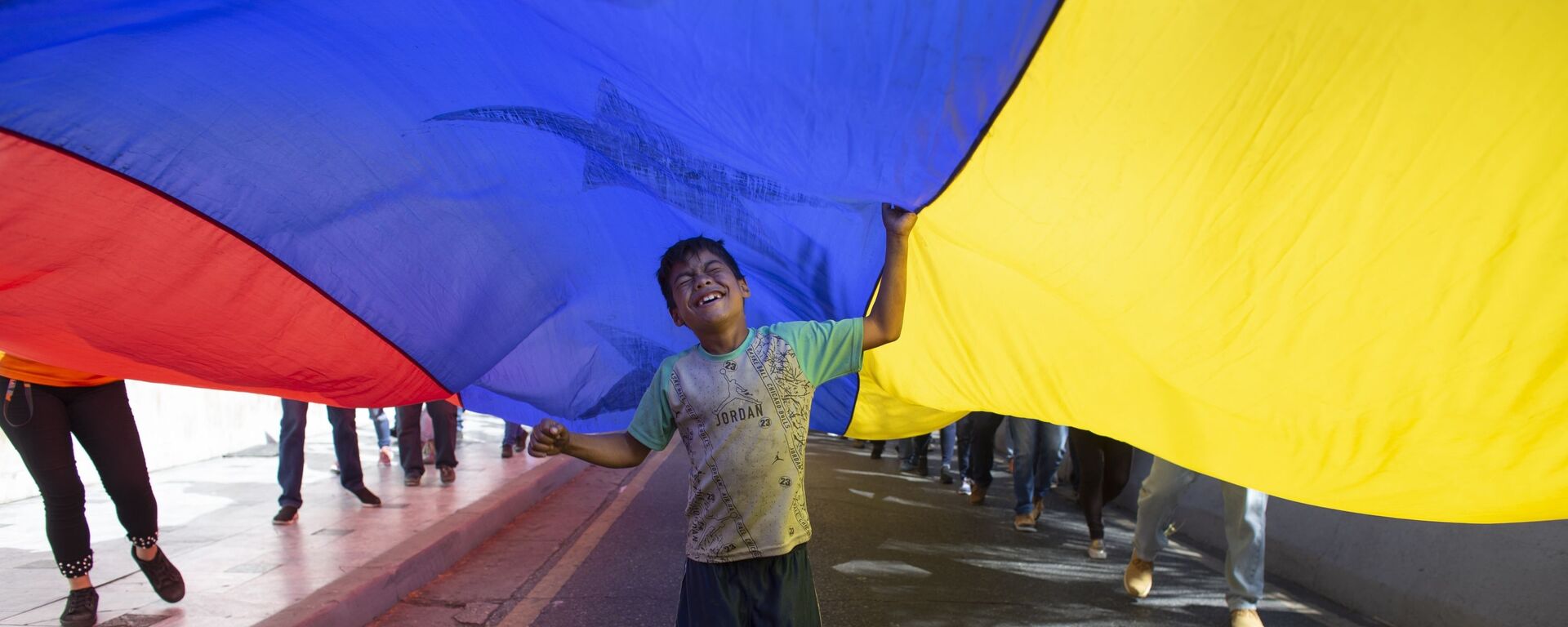 Un niño juega bajo una bandera venezolana - Sputnik Mundo, 1920, 02.02.2022