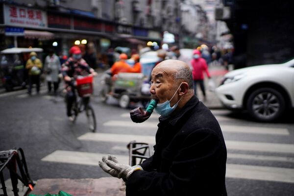 La ciudad de Wuhan, ubicada en la provincia de Hubei, en el centro de China, ha vuelto a reactivarse tras un aislamiento total y una cuarentena severa. Hoy en día, es difícil creer que solo hayan pasado unos meses de aquello, los únicos recordatorios de esos tiempos son las mascarillas en los rostros de los residentes locales y los controles sanitarios que permanecen vigentes en los lugares públicos.En la foto: Un hombre con una pipa en una de las calles de Wuhan. - Sputnik Mundo