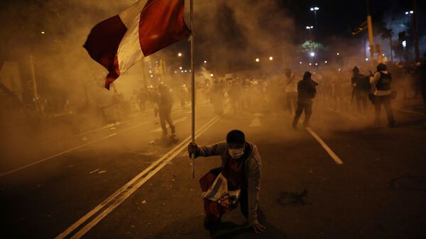 Un manifestante sostiene la bandera de Perú mientras la Policía reprime una protesta - Sputnik Mundo