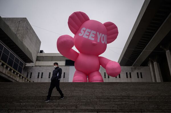 Un hombre con la mascarilla baja por las escaleras del teatro Sejong en Seúl, Corea del Sur, con un oso inflable en el fondo.  - Sputnik Mundo