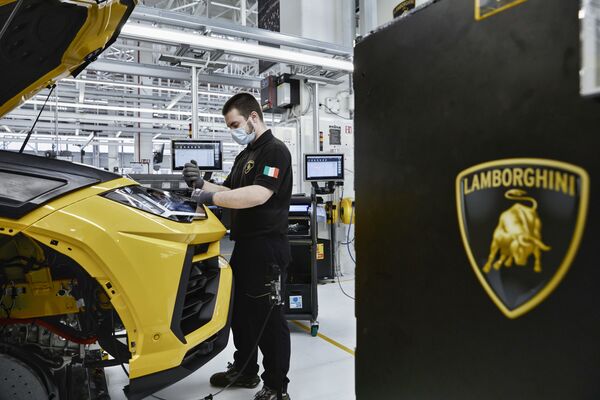 El toro dorado también adorna el emblema de Lamborghini simbolizando el poder de estos coches deportivos. En la foto: un trabajador en la línea de montaje de la planta de Lamborghini en Sant'Agata Bolognese, Italia, 2020. - Sputnik Mundo