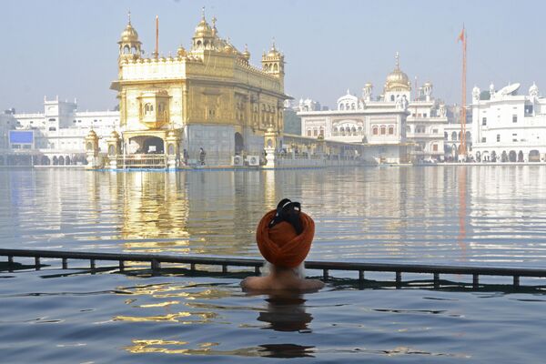 Un sij se baña en el lago sagrado de Amrit Sarovar cerca del Templo Dorado de Amritsar, en la India. La leyenda dice que hace muchos siglos las aguas de Amrit Sarovar curaron a un hombre que estaba desesperadamente enfermo, y los sijs construyeron un templo a orillas del lago.  - Sputnik Mundo