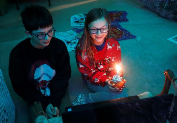Dos niños durante un Christingle virtual, donde sostienen una vela que simboliza la luz del mundo y celebran el nacimiento de Jesucristo. Blakesley, Reino Unido. - Sputnik Mundo