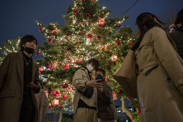 Una pareja se fotografía con un árbol de Navidad en Tokio, Japón. - Sputnik Mundo