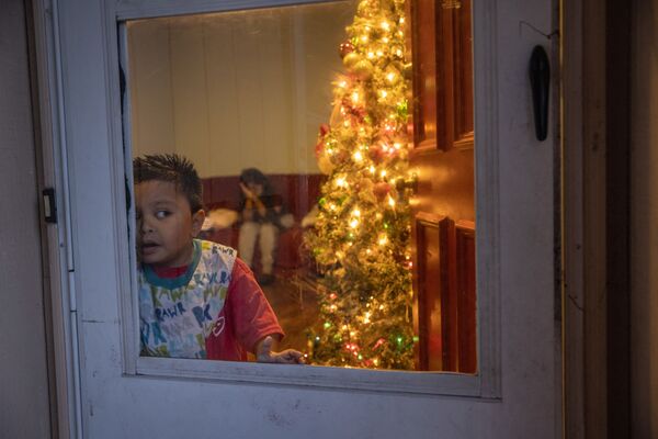 Mario, un niño migrante guatemalteco de 7 años cuyos parientes están enfermos con coronavirus, mira por la ventana en Navidad en Stamford, estado de Connecticut en EEUU. - Sputnik Mundo