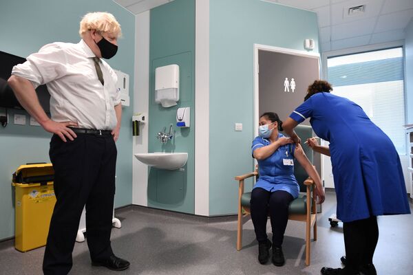 El primer ministro británico, Boris Johnson, observa cómo Jennifer Dumasi recibe la vacuna británica contra el COVID-19 desarrollada conjuntamente por la Universidad de Oxford y AstraZeneca durante su visita al Chase Farm Hospital, en el norte de Londres, Reino Unido. - Sputnik Mundo