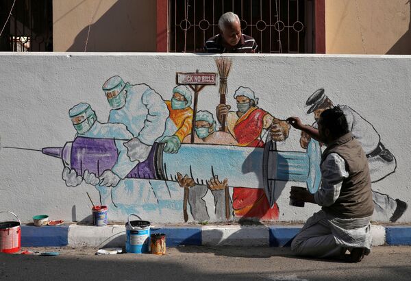 Un hombre termina un grafiti que representa una vacuna en Calcuta, la India. - Sputnik Mundo