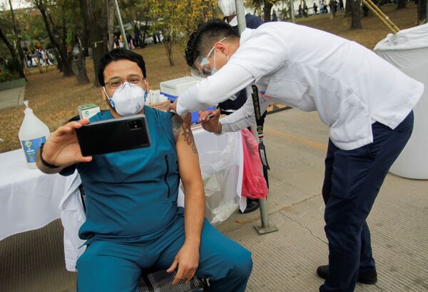 Un trabajador médico se toma una selfie mientras recibe una inyección con una dosis de la vacuna estadounidense-alemana Pfizer-BioNTech contra el COVID-19 en el Hospital Militar Regional de Especialidades en San Nicolás de los Garza, en las afueras de Monterrey, México. - Sputnik Mundo