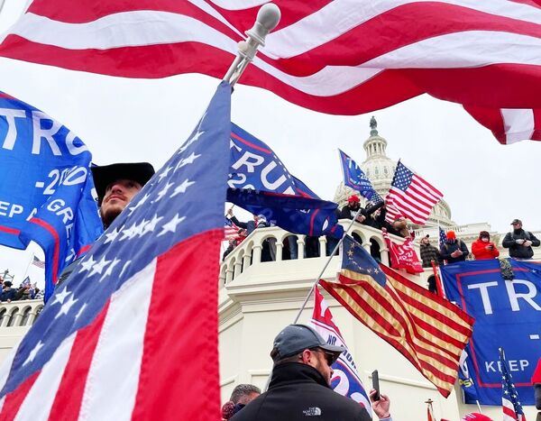 Unos manifestantes ondean banderas de EEUU y telas con lemas en apoyo a Donald Trump frente al Capitolio, en Washington. - Sputnik Mundo