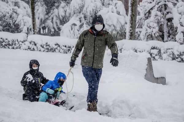 Un hombre lleva a unos niños en un trineo durante una fuerte nevada en Rivas Vaciamadrid, municipio del área metropolitana de Madrid. - Sputnik Mundo