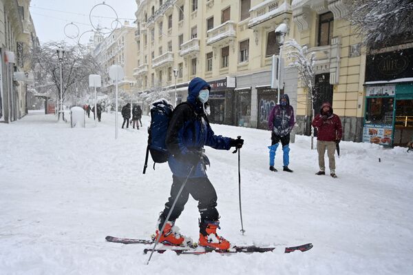 Una mujer utiliza esquíes para desplazarse por la nieve que cubre la capital de España. - Sputnik Mundo