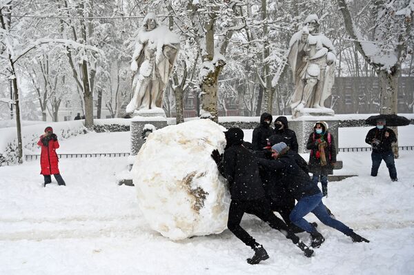 Unos jóvenes hacen una bola de nieve gigante en Madrid después de una fuerte nevasca. - Sputnik Mundo
