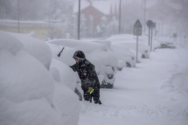 Un hombre quita la nieve de su automóvil durante una nevasca en Rivas Vaciamadrid. - Sputnik Mundo