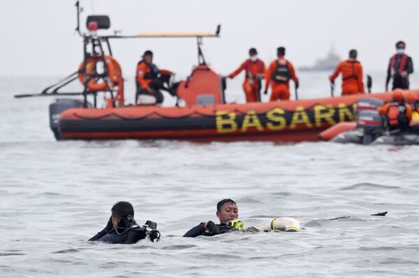Buzos de la Armada de Indonesia sacan del agua restos de la aeronave durante la operación de búsqueda. - Sputnik Mundo