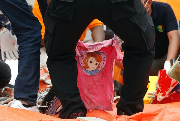 Rescatistas indonesios manipulan una camiseta rosada encontrada durante las operaciones de búsqueda en el mar de Java. - Sputnik Mundo