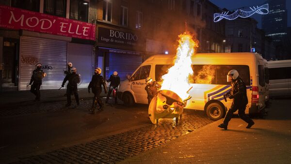 Agentes de la Policía intentan extinguir el fuego durante las protestas en Bruselas (Bélgica), el 14 de enero de 2021 - Sputnik Mundo