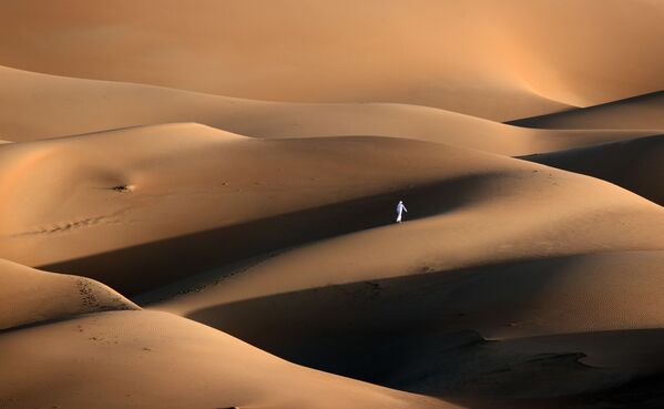 Un habitante de los Emiratos Árabes Unidos atraviesa dunas arenosas del desierto de Liwa. - Sputnik Mundo