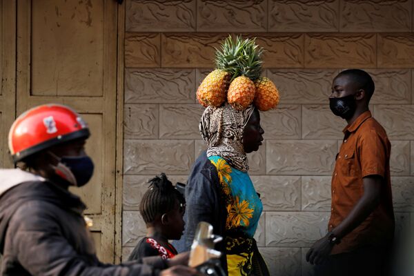 Una habitante traslada piñas sobre su cabeza en la ciudad de Kampala, Uganda.   - Sputnik Mundo