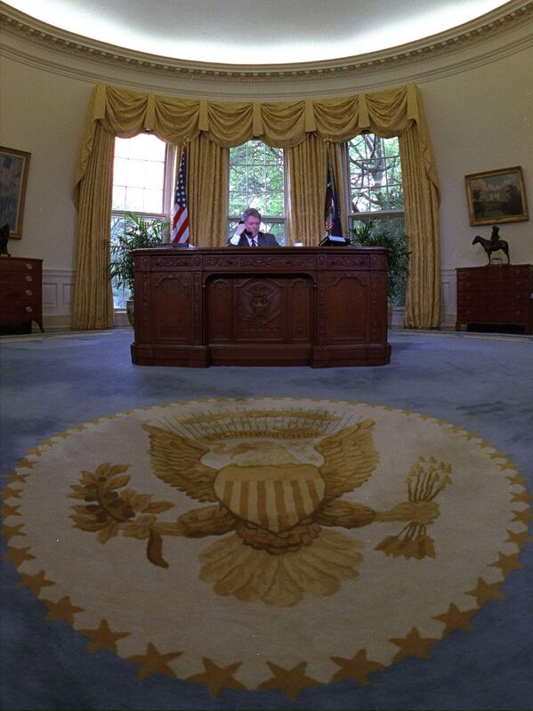 Las cortinas y la alfombra utilizadas en el despacho Oval por Bill Clinton durante sus ocho años al mando de EEUU son las mismas que utiliza ahora Biden.En la foto: Clinton habla por teléfono en el Despacho Oval (1993). - Sputnik Mundo