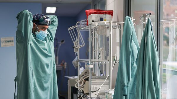 Un trabajador sanitario se prepara para tratar a un paciente que padece la enfermedad por coronavirus - Sputnik Mundo