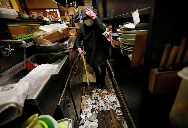 La propietaria de un bar japonés, Mitsue Hisa, de 70 años, recoge los platos rotos después del fuerte sismo. - Sputnik Mundo
