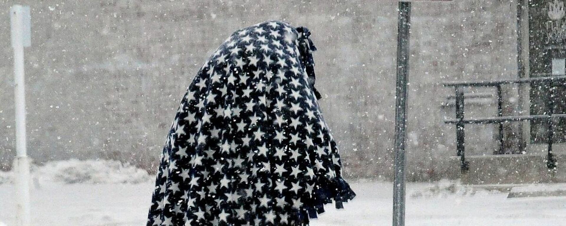Una persona camina cubierta por una manta para mantenerse caliente después de una tormenta de nieve en el centro comercial de Wooster, Ohio, EEUU, el 15 de febrero de 2021. 
 - Sputnik Mundo, 1920, 17.02.2021
