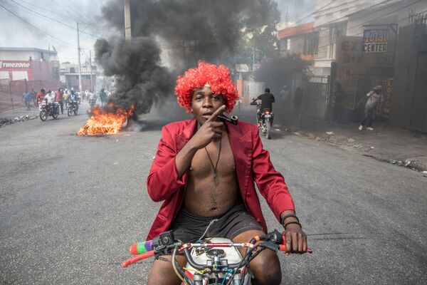 Un hombre se desplaza en bicicleta en medio de las marchas realizadas en Puerto Príncipe, Haití, para protestar contra el gobierno del presidente Jovenel Moise. - Sputnik Mundo