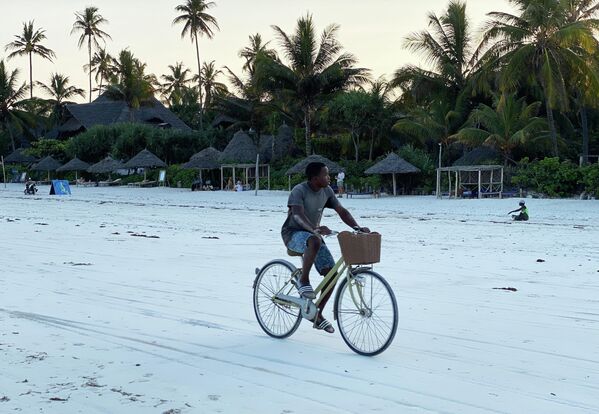Un joven monta en bicicleta por una playa. - Sputnik Mundo