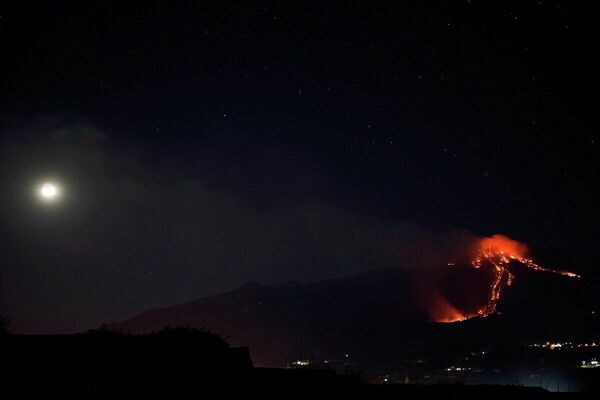 El volcán más activo de Europa, el Etna, entra en erupción con sus corrientes de lava al rojo vivo y cubre el cielo nocturno de la ciudad italiana de Giarre, región de Sicilia, el 16 de febrero.  - Sputnik Mundo