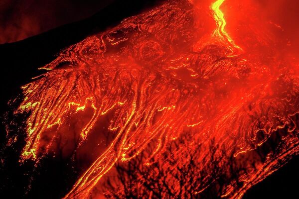El Etna continúa en erupción con sus enormes corrientes de lava al rojo vivo y cubre el cielo nocturno del pueblo italiano de Fornazzo, el 23 de febrero. - Sputnik Mundo