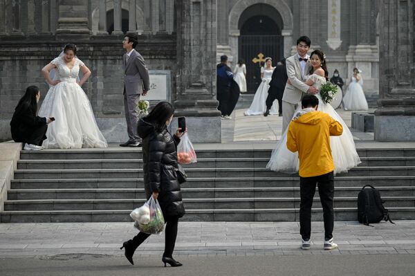 Unos recién casados se sacan fotos junto a la entrada a un templo en Pekín, China. - Sputnik Mundo