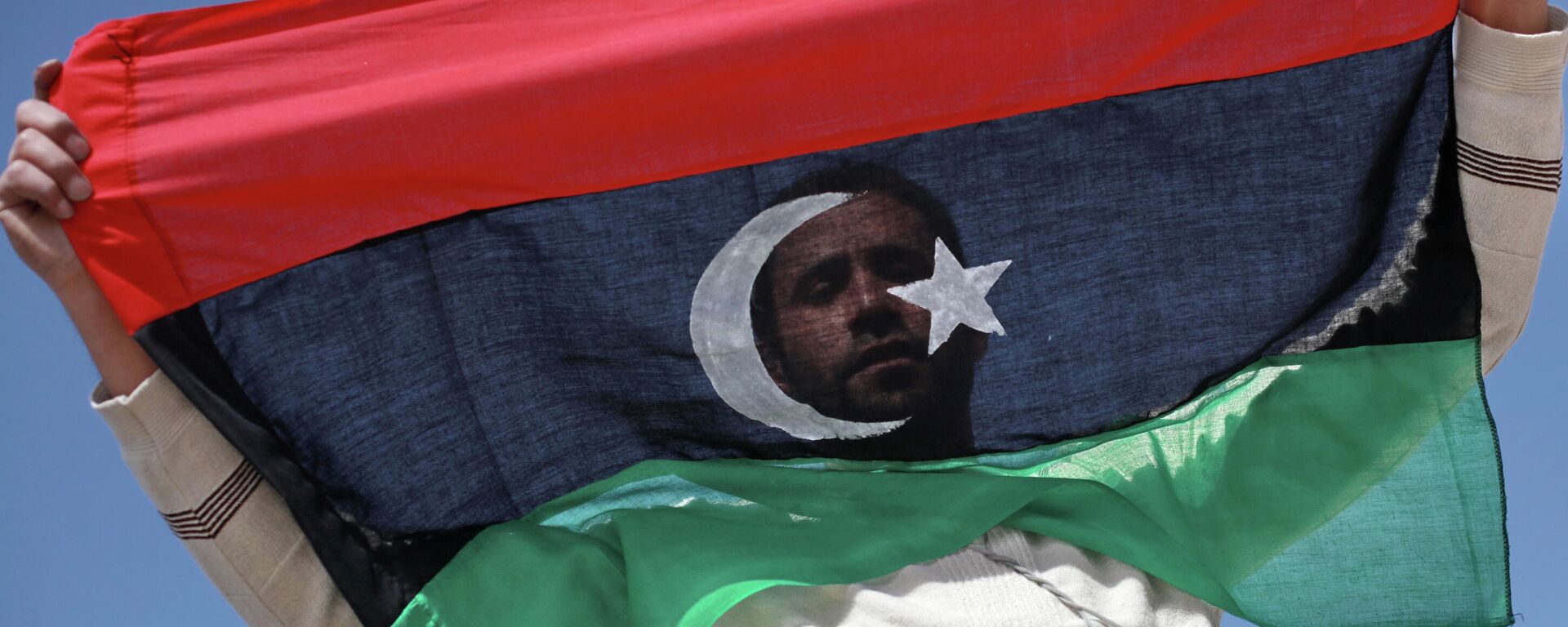 Un opositor con la bandera de Libia - Sputnik Mundo, 1920, 25.10.2021
