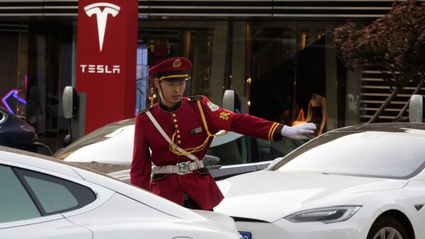 Un guardia de seguridad dirige el tráfico cerca de una estación de carga de Tesla en Pekín, China. - Sputnik Mundo