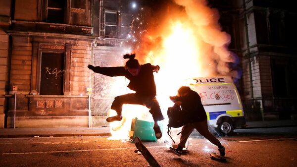Демонстрант катается на скейтборде перед горящей полицейской машиной во время акции протеста в Бристоле, Великобритания - Sputnik Mundo