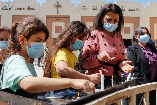 La gente enciende velas para celebrar una misa de Pascua fuera de la Iglesia Caldea de San Elya en medio del brote de coronavirus en Bagdad (Iraq). - Sputnik Mundo