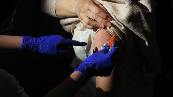Un trabajador sanitario suministra la vacuna contra el Covid-19 a una persona, en el Centro Cultural Miguel Delibes - Sputnik Mundo